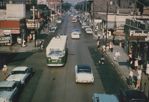 A green and cream Chicago Transit Authority trolleybus marked with route 36 and fleet number 9417 moves down a sunlit street lined with 1950s cars and pedestrians, with storefronts for Hyde Park Bible Church and Florsheim visible on either side.