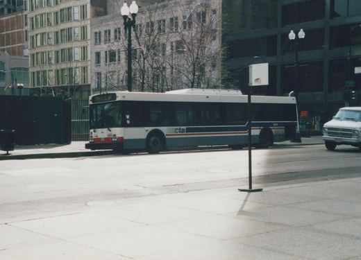 A white, blue, and red Chicago Transit Authority bus, number 5844, is parked on a city street with bare trees and snow on the ground, with a white van parked nearby.