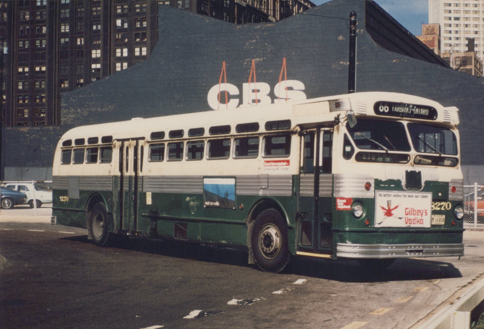A vintage green and cream motor bus with the number 3270, operated by the Chicago Transit Authority, is shown parked on a city street with a large CBS billboard behind it.