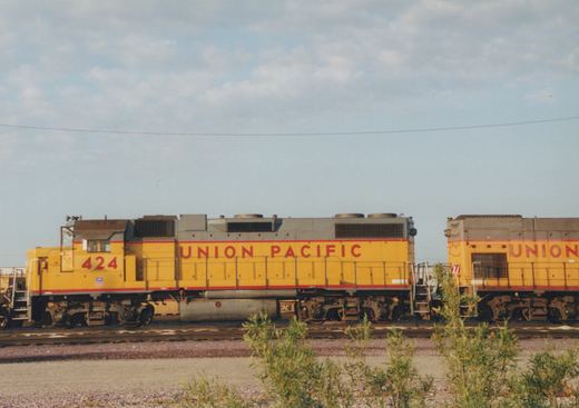 Two yellow Union Pacific diesel locomotives on a track at a rail yard, with the lead unit numbered 424.