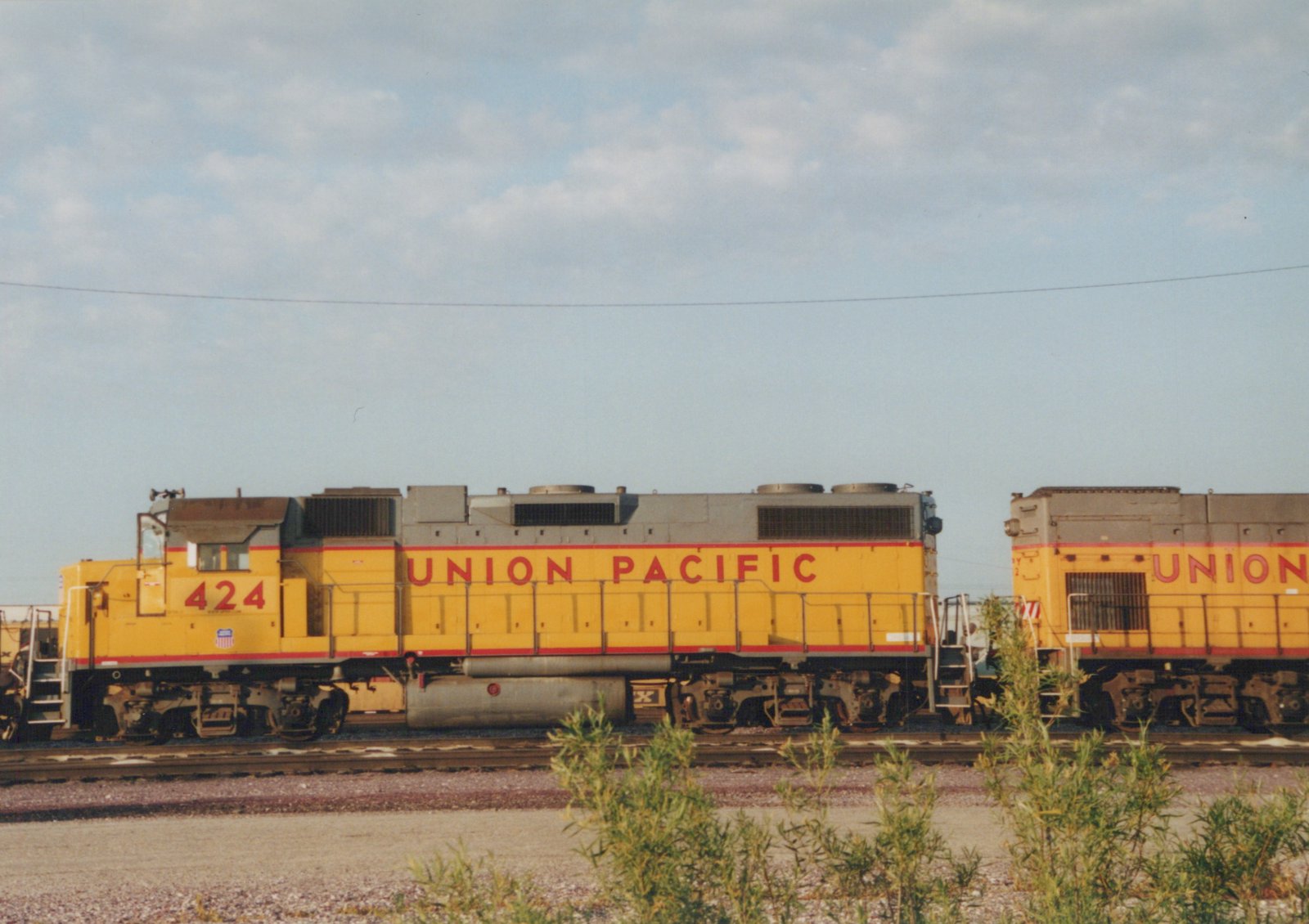 Two yellow Union Pacific diesel locomotives on a track at a rail yard, with the lead unit numbered 424.