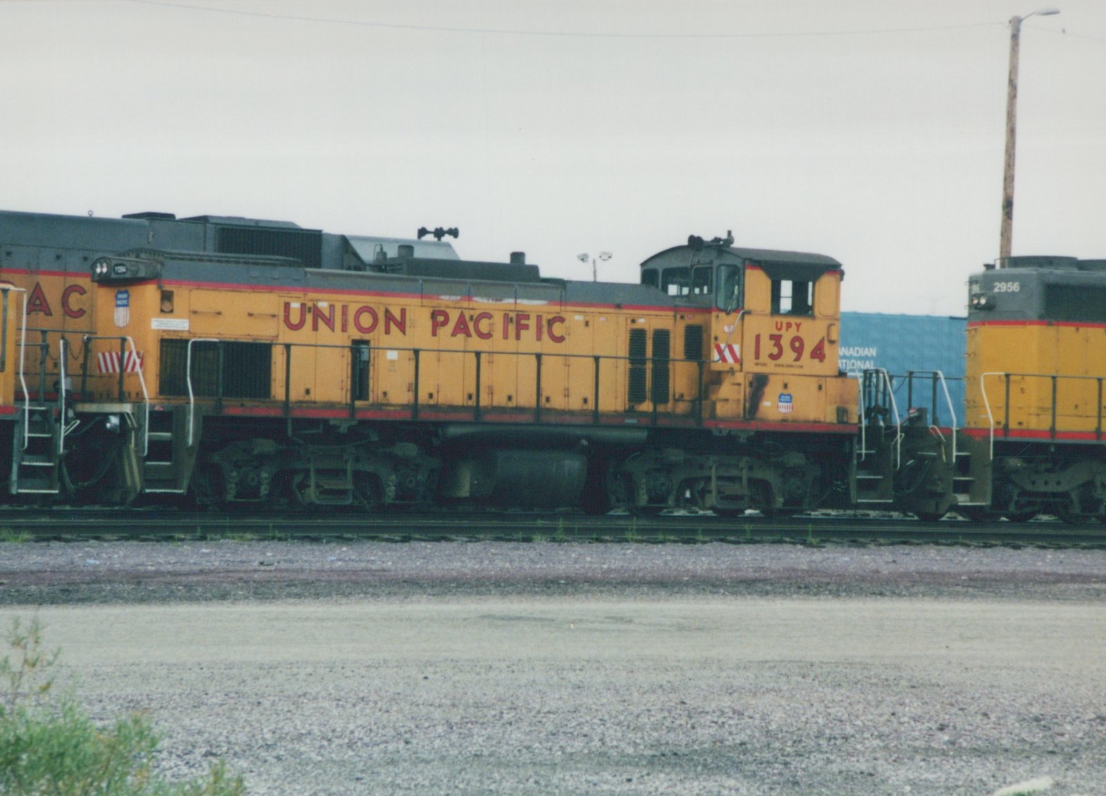 Side view of a yellow Union Pacific GP9 diesel locomotive, number 1394, on a railroad track under an overcast sky.