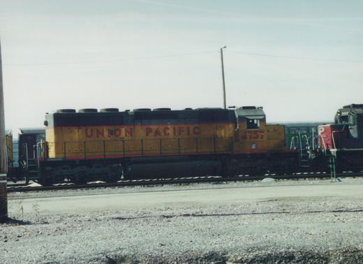 A side view of a Union Pacific diesel locomotive numbered 4757 in a railroad yard, with a second locomotive visible behind it.