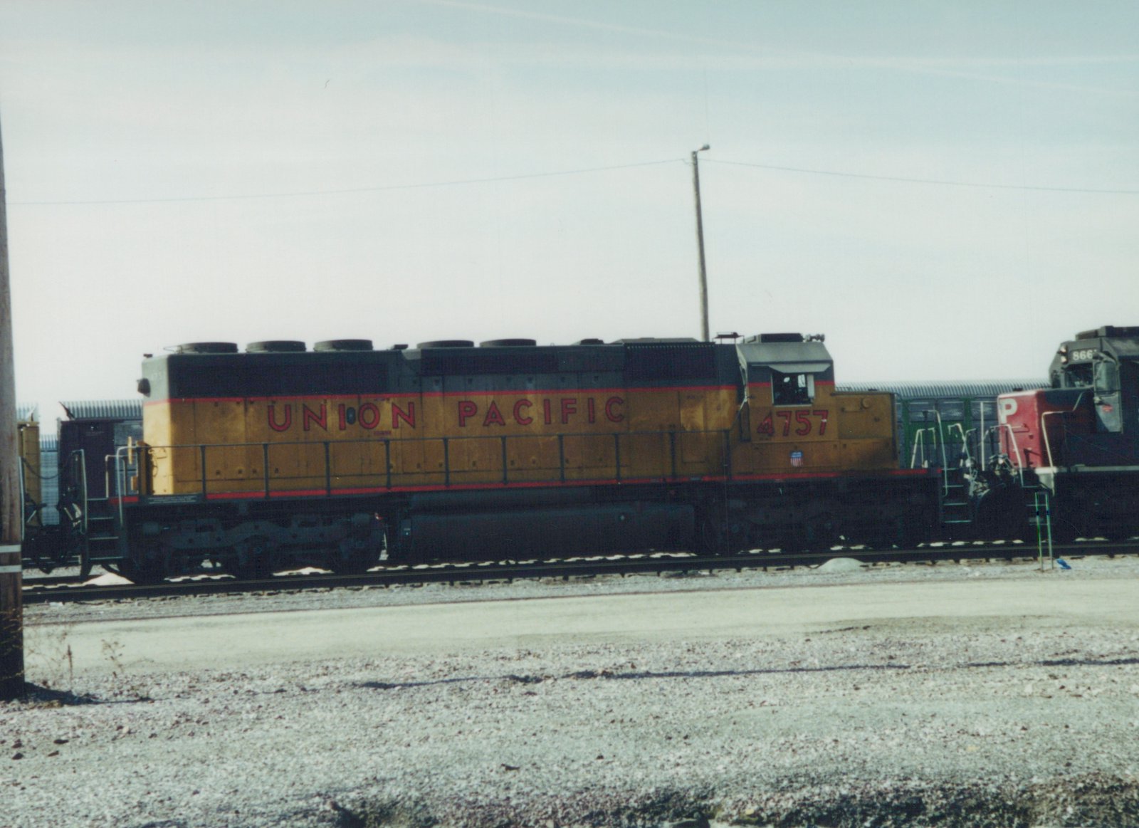 A side view of a Union Pacific diesel locomotive numbered 4757 in a railroad yard, with a second locomotive visible behind it.