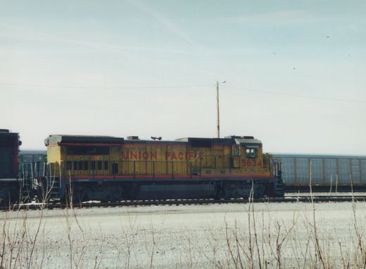 A yellow Union Pacific diesel locomotive, number 5634, stands on a track in a snowy yard, with a freight car behind it.