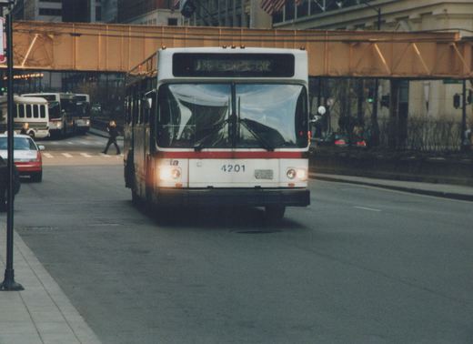 A white and red CTA bus numbered 4201 with destination 136 Eastgate Express approaches on a city street, with an elevated train structure overhead and pedestrians crossing.