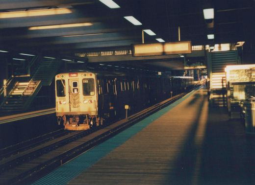 A cream-colored CTA subway train with the number 715 and a 'Loop' destination sign is stopped at an underground station platform.