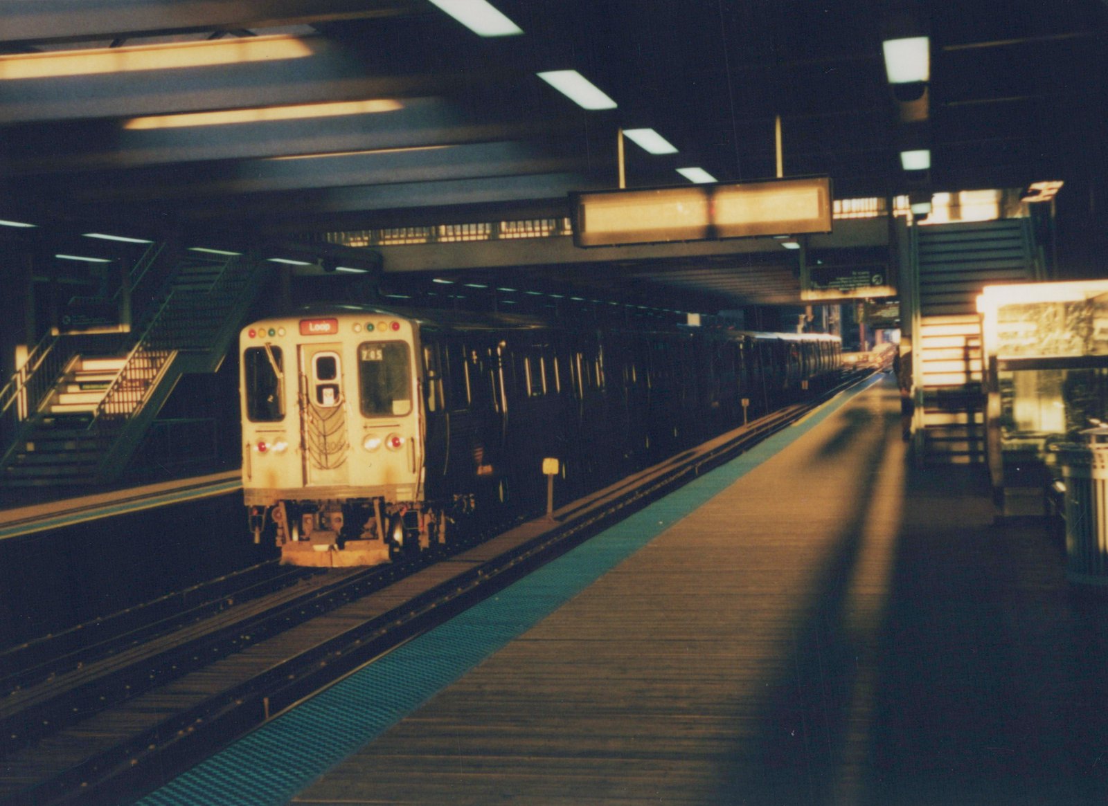 A cream-colored CTA subway train with the number 715 and a 'Loop' destination sign is stopped at an underground station platform.