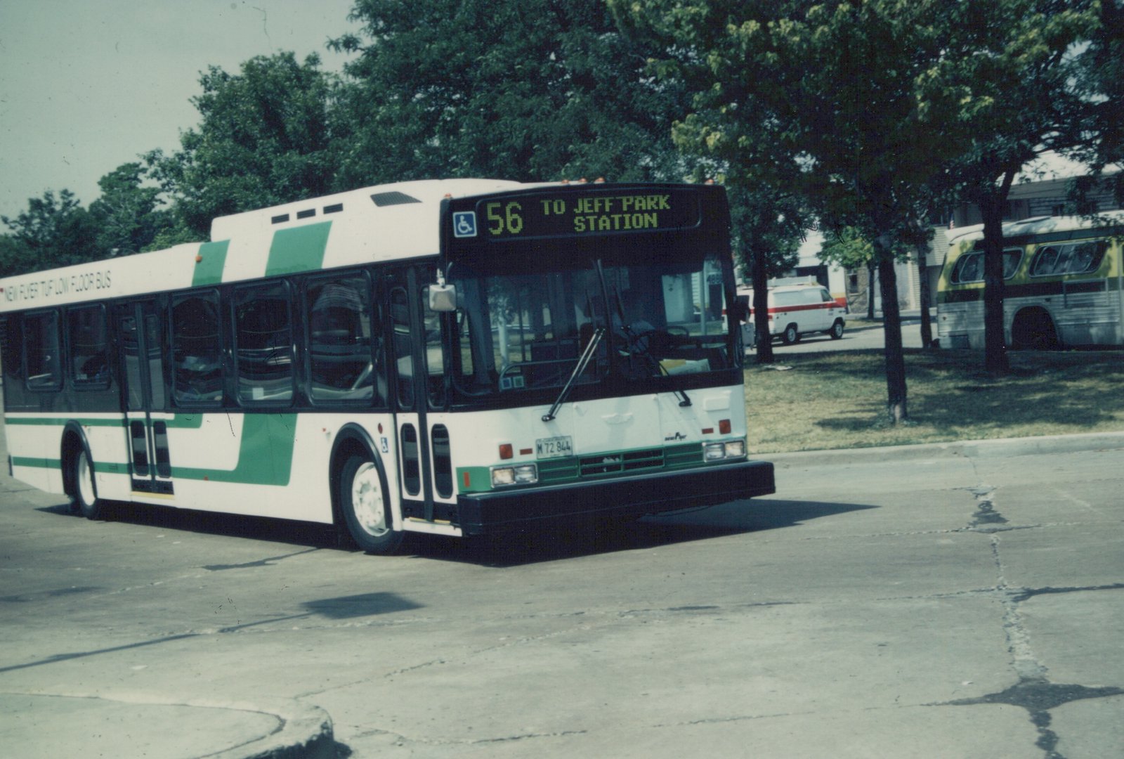 A white and green Pace bus numbered 4882, route 56 to Jefferson Park Station, is parked on a sunny street with trees and another bus in the background.
