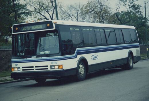 A side-front view of a white and blue RTA bus with the number 110 on the front and side, displaying route 22 to Howard, parked on a street lined with trees.
