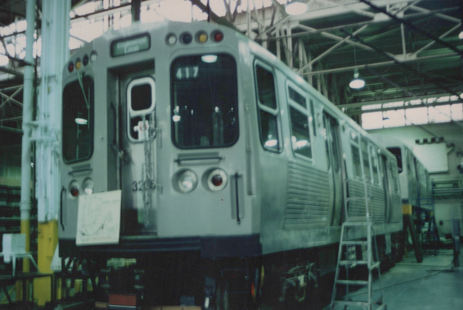 A silver CTA rapid transit car is parked inside a large shop with its front number 3205 and destination sign visible.