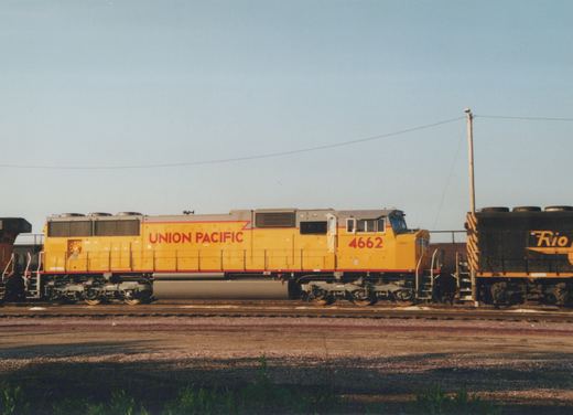 Two diesel locomotives on parallel tracks: a yellow Union Pacific SD40-2 with the number 4662, and a black Rio Grande GP9 with yellow lettering.