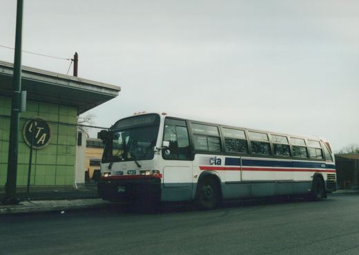 A white and blue Chicago Transit Authority bus, number 4739, is parked on a street with a green building featuring an 'LTA' sign in the background, under an overcast sky.