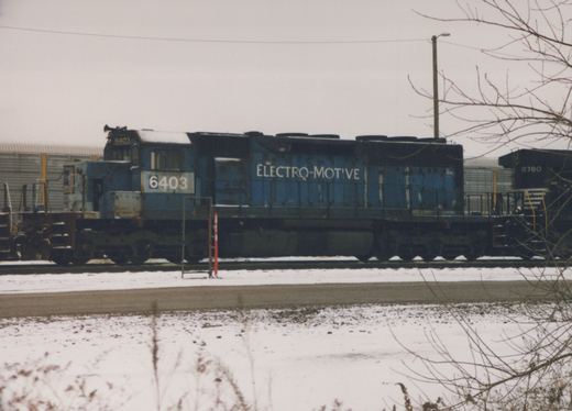 A side view of a blue EMD SD40 locomotive numbered 6403 in a snowy yard, with another locomotive, number 8780, visible behind it.