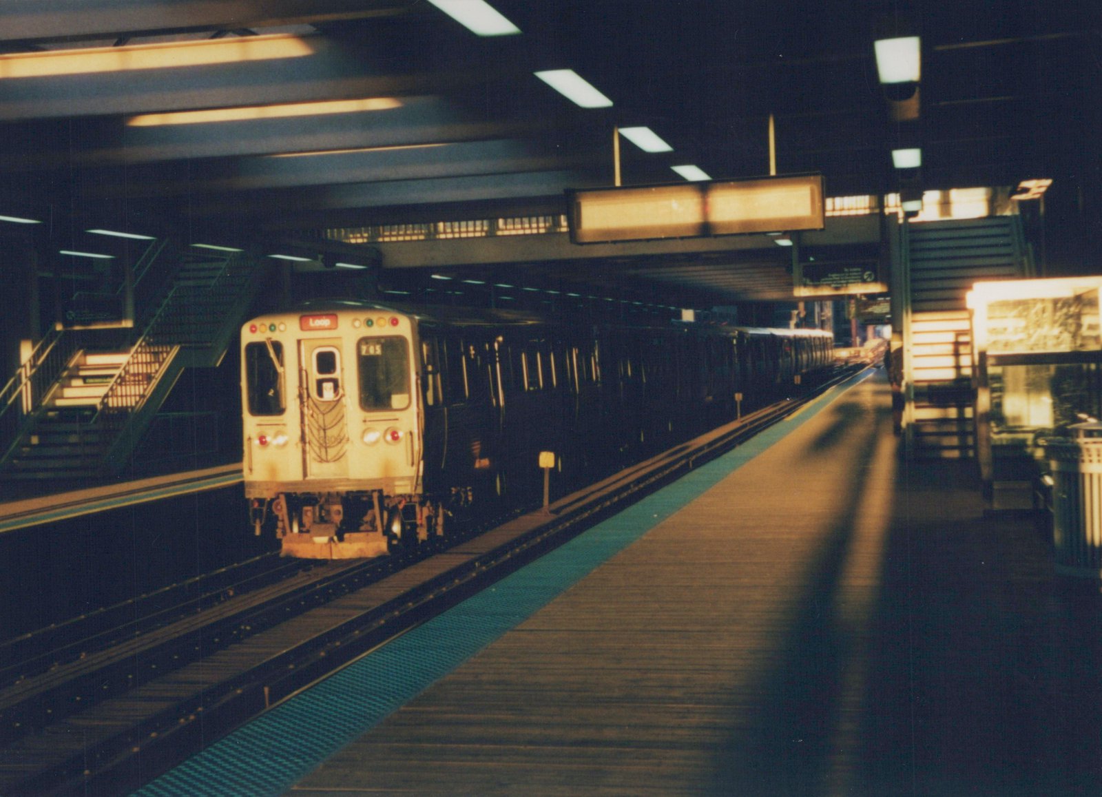 A cream and black Chicago Transit Authority 'L' train, car number 715, is stopped at a dimly lit subway station platform with its destination sign showing 'Loop'.