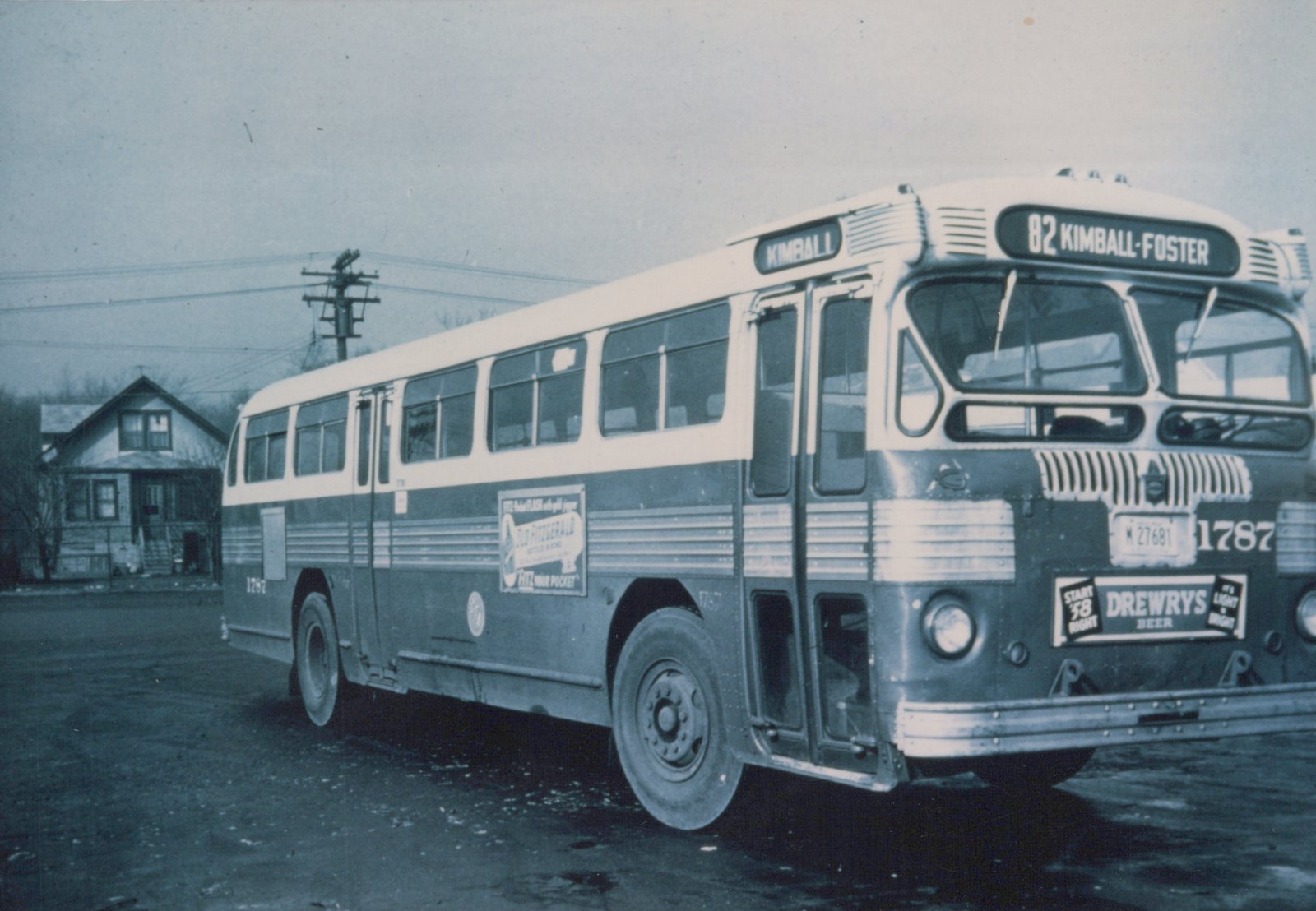 A three-quarter front view of a dark green and white CTA motor bus with number 1787 on its side and front, showing a '82 KIMBALL-FOSTER' destination sign and vintage advertisements on its bumper and side.