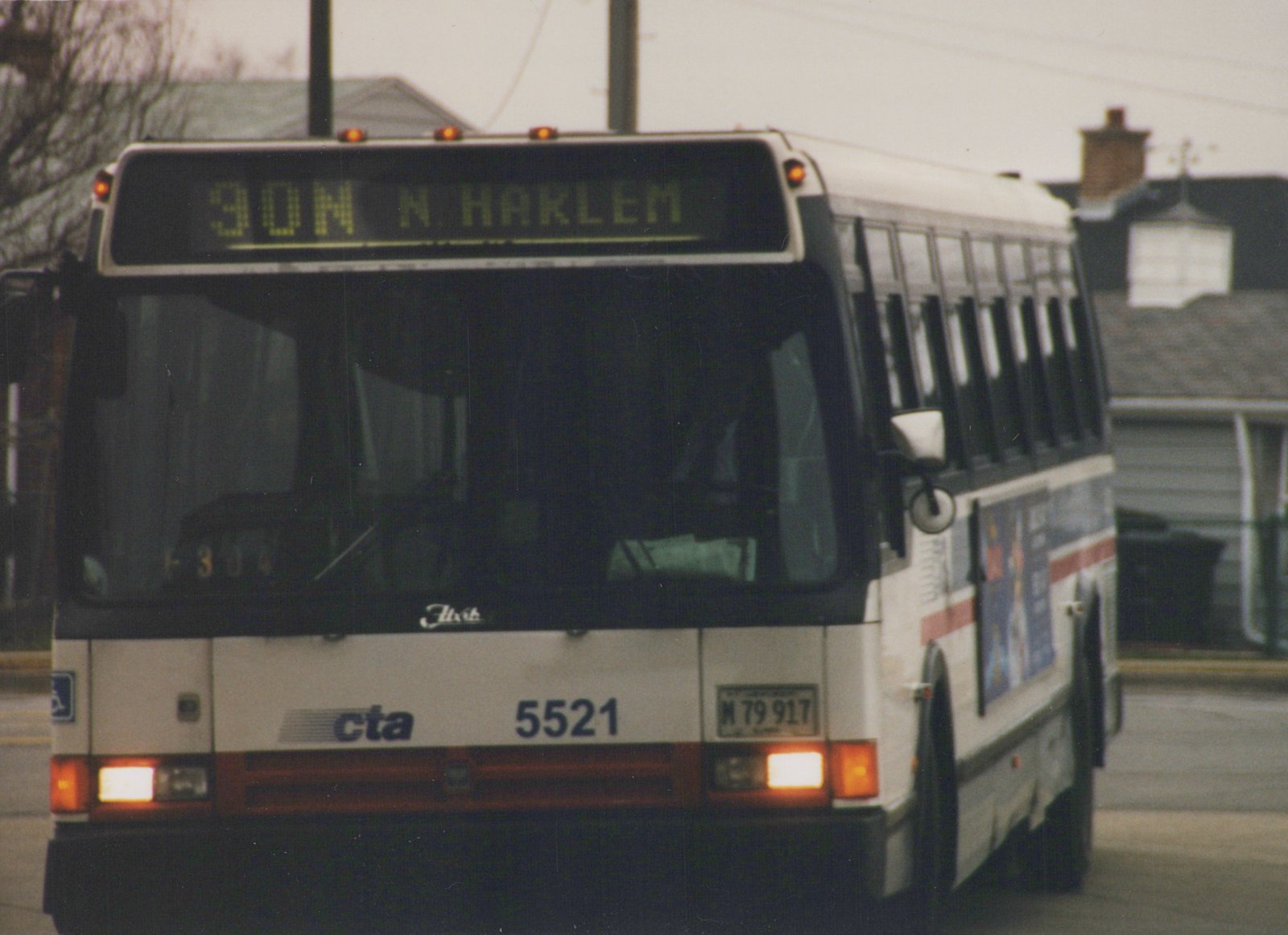 Front three-quarter view of a white CTA bus with red and blue stripes, showing destination 90N N. HARLEM and fleet number 5521, against a residential street background on an overcast day.