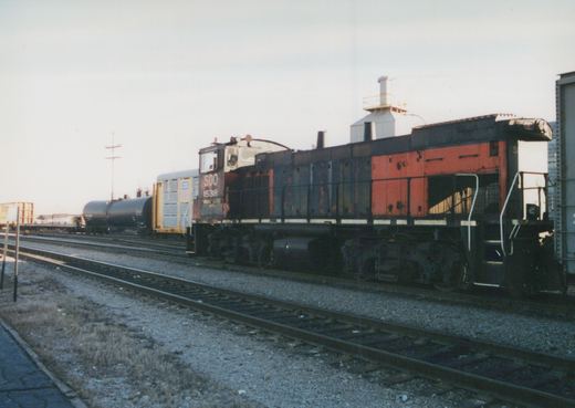 Soo Line EMD SD9 locomotive number 1538, painted in red and black, is on a set of tracks in a rail yard under an overcast sky with freight cars behind it.