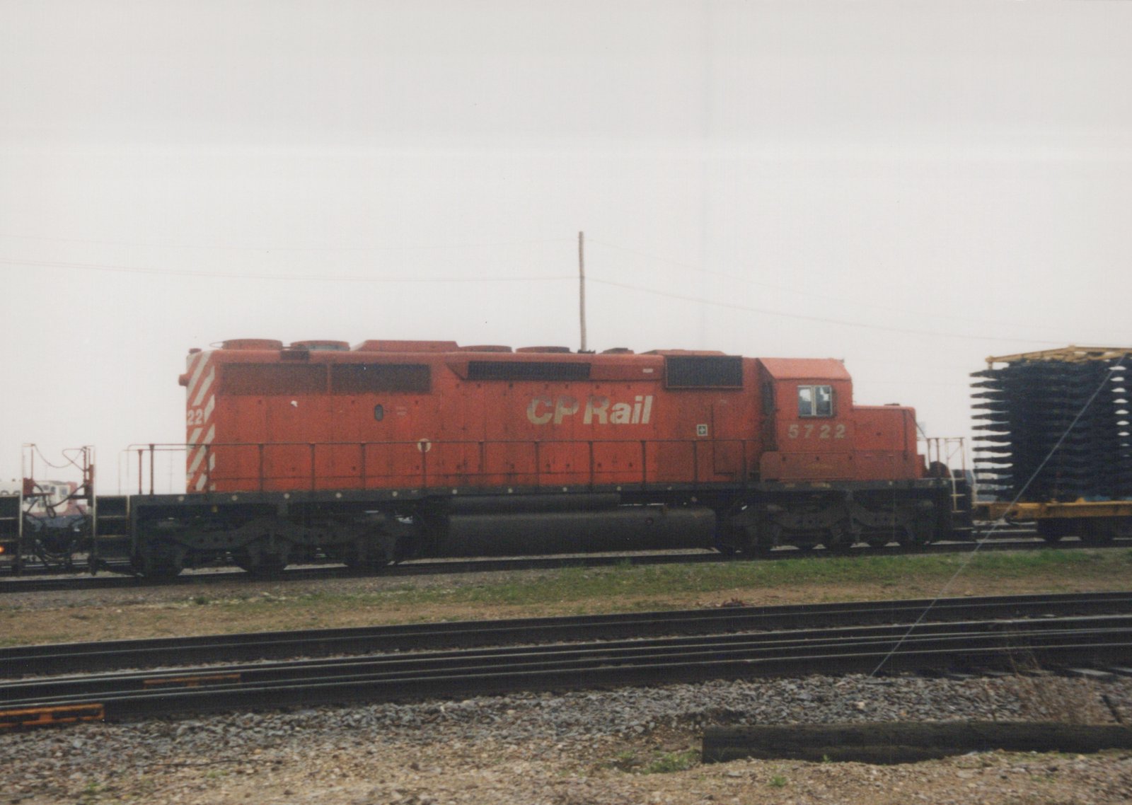 A side view of a red Canadian Pacific diesel locomotive, number 5722, parked on tracks in a yard under an overcast sky.