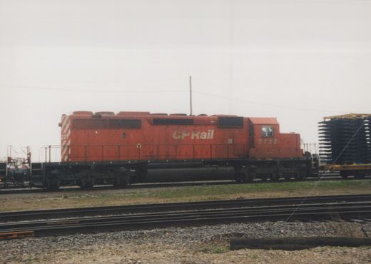 A side view of a red Canadian Pacific diesel locomotive, number 5722, parked on tracks in a yard under an overcast sky.
