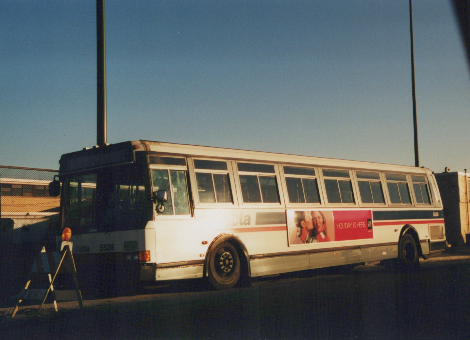 A white Chicago Transit Authority bus numbered 5528 is parked on a street, displaying a red and white GAP advertisement on its side, under a clear blue sky.