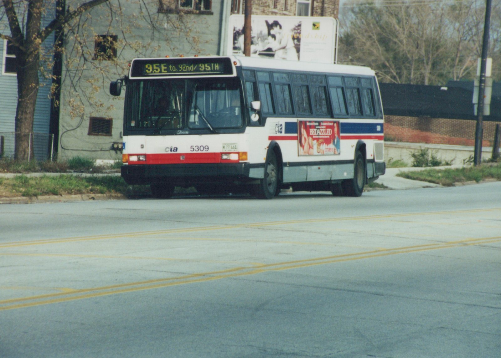 A white, red, and blue CTA bus with the number 5309 is driving on a street, displaying a destination sign for route 95E to 92nd/95th. A billboard and trees are visible in the background.