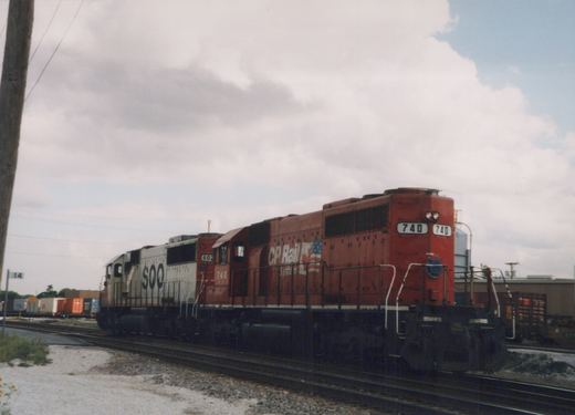 A red CP Rail System diesel locomotive numbered 740 is shown in a three-quarter front view, coupled with a white SOO Line locomotive numbered 602, on railroad tracks in a yard with overcast weather.