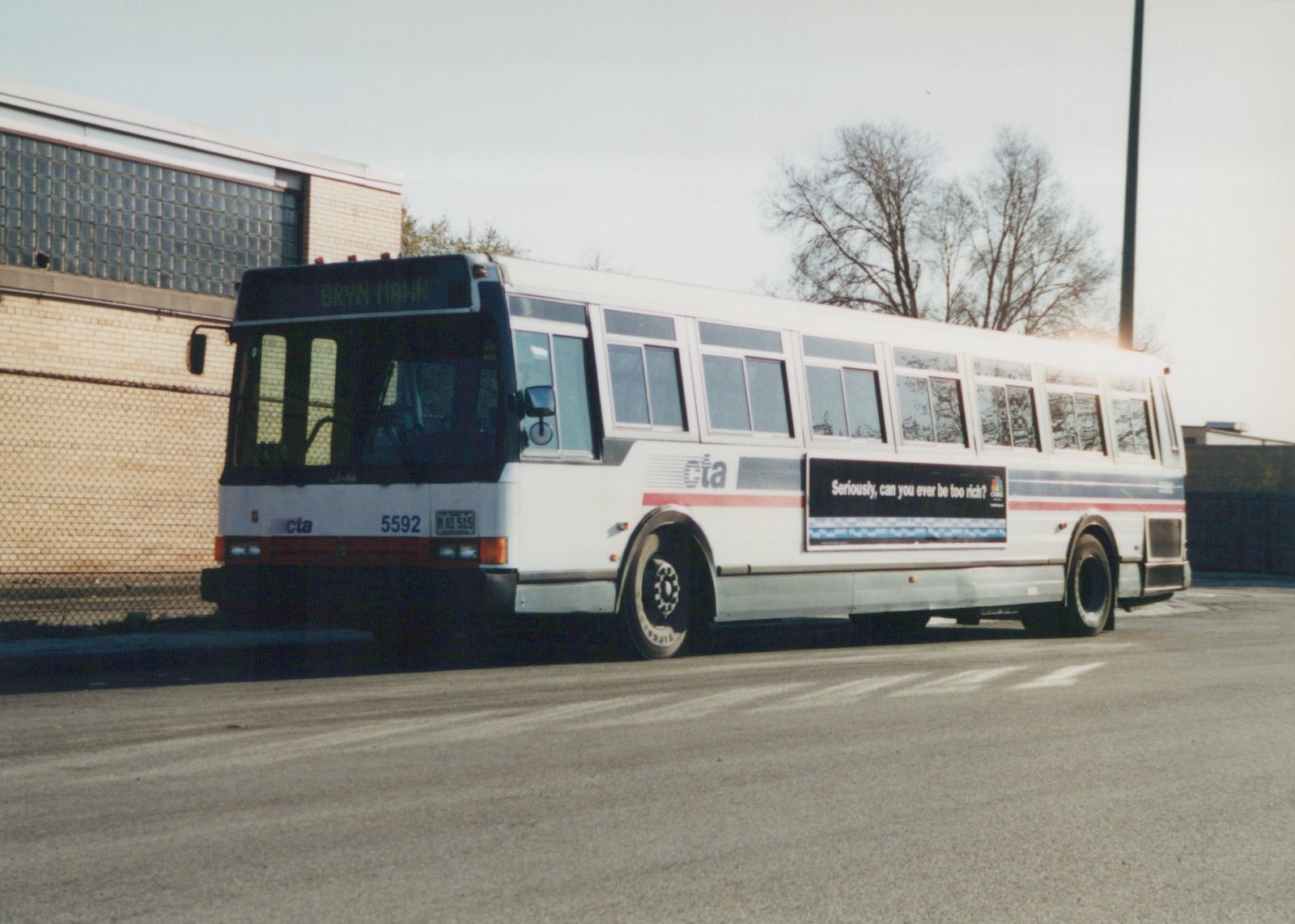 A white CTA bus with blue and red stripes, numbered 5592, parked in front of a brick building with a destination sign reading 'BRYN MAWR' and an advertisement on its side.