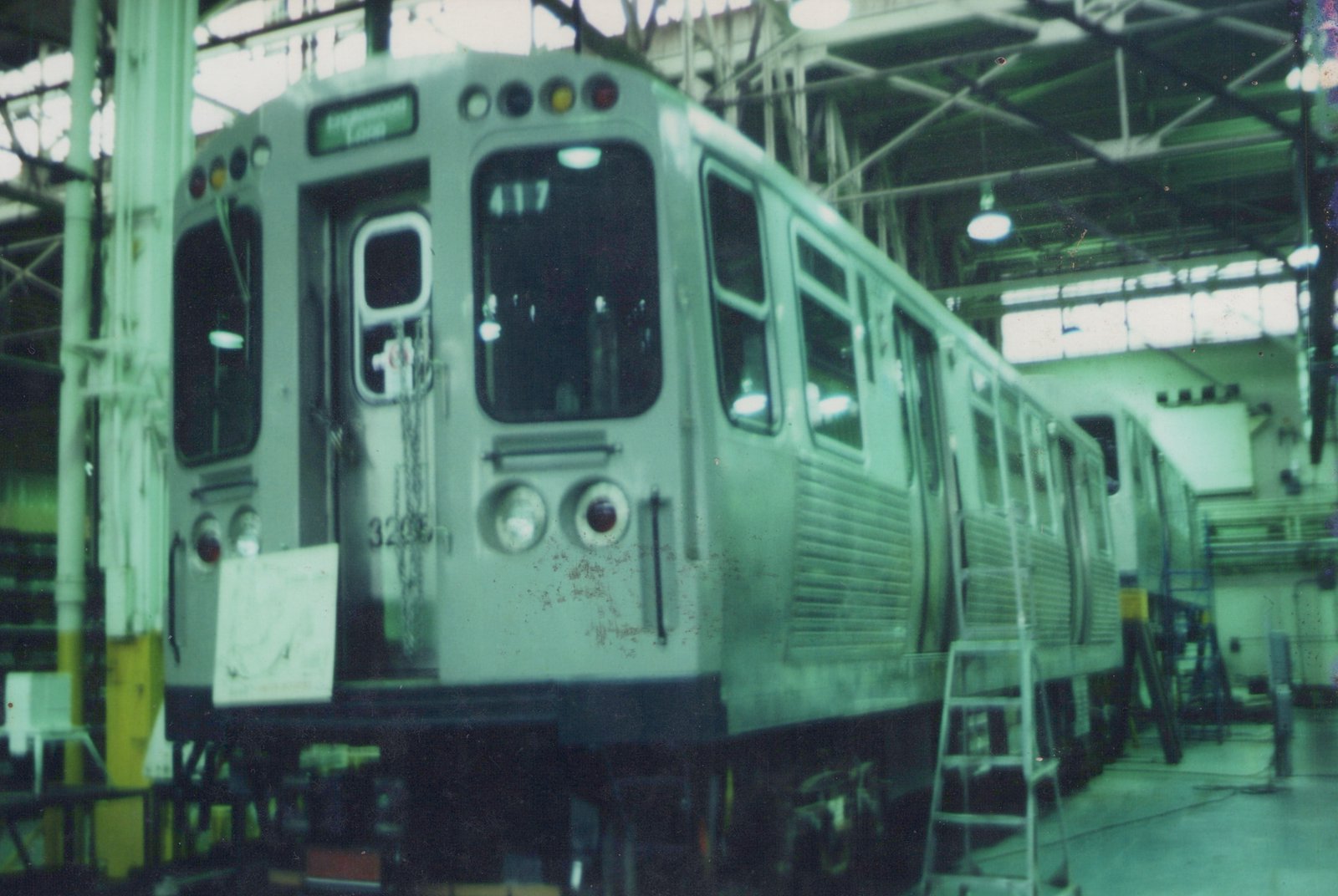 A silver CTA 2000-series rapid transit car, numbered 4117, is shown from a three-quarter front view inside a spacious carbarn, with another car, 3206, visible behind it.