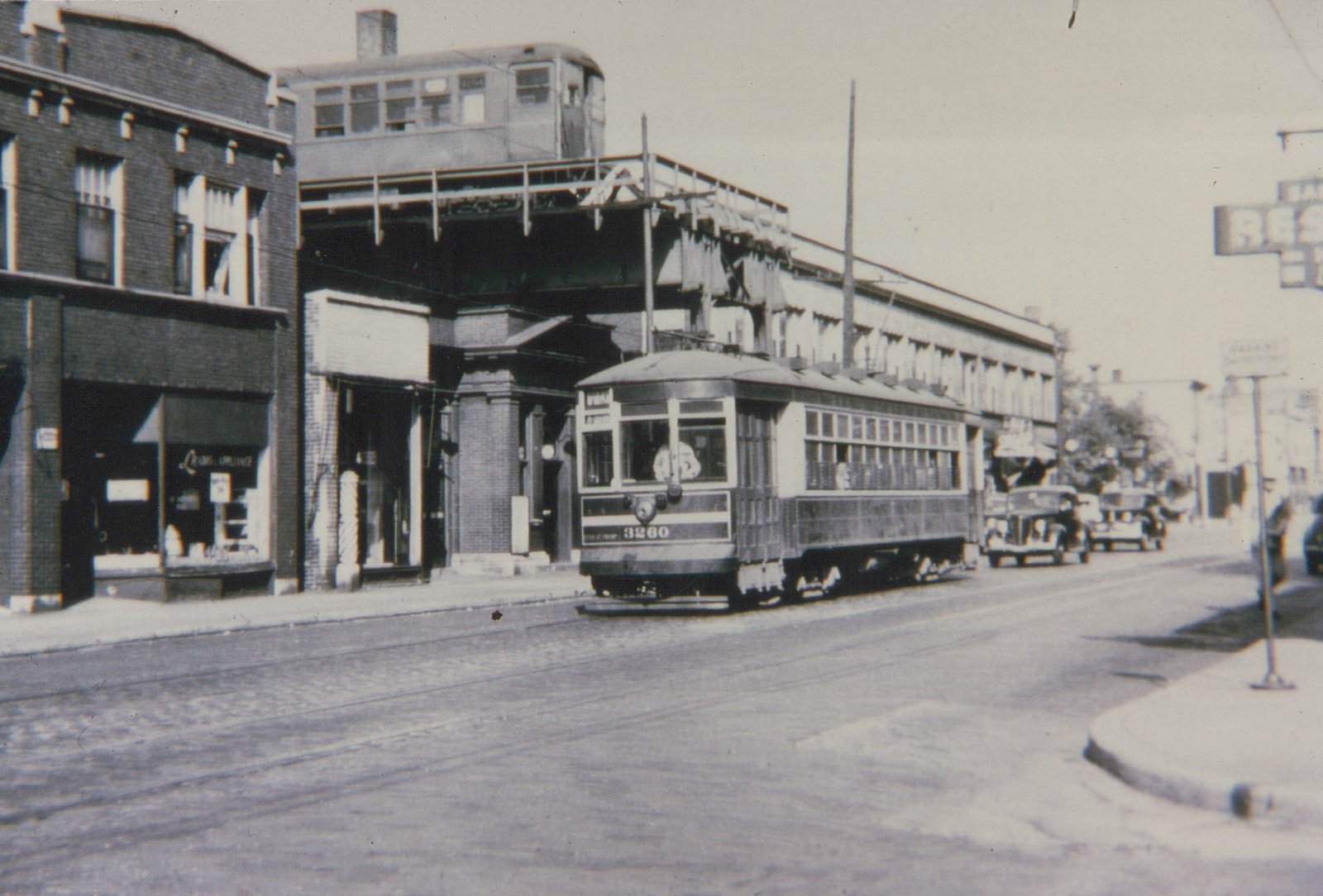 A black-and-white street scene from the 1930s showing a Chicago Surface Lines streetcar numbered 3260 on the street, with a Chicago Rapid Transit Company elevated car visible on the structure above.