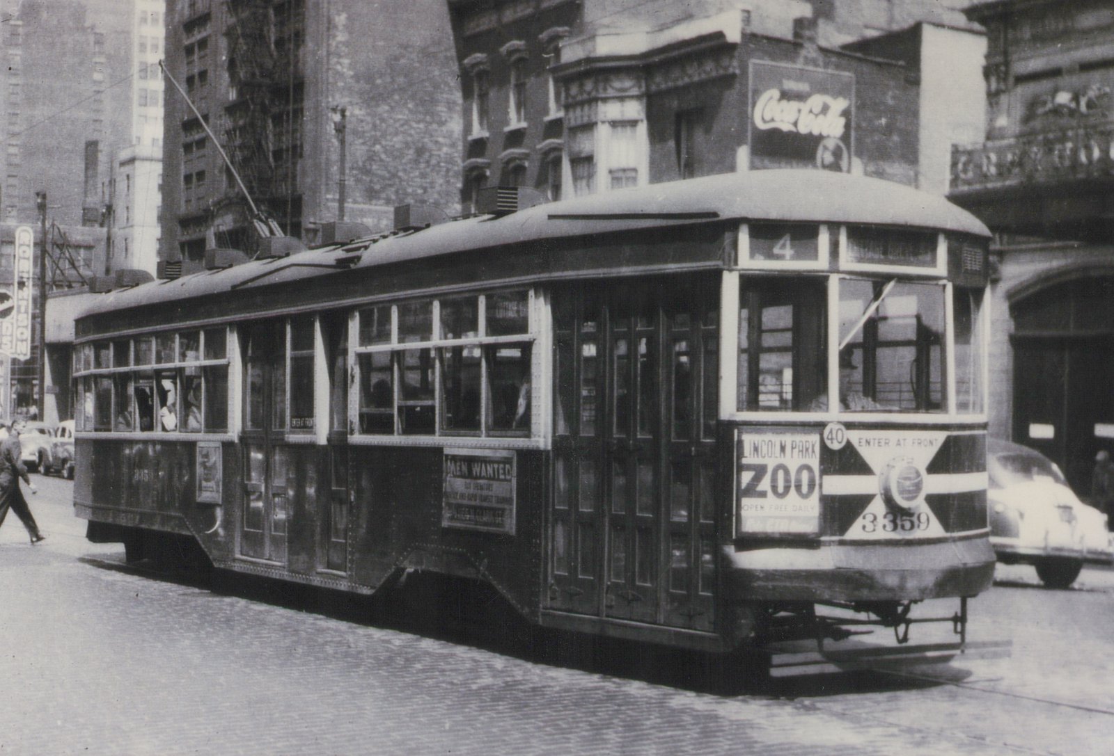 A black-and-white photo of a vintage Birney streetcar, number 3359, from Chicago Surface Lines, running on a city street with a Coca-Cola sign visible on a building behind it.