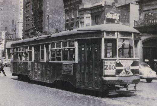 A black-and-white photo of a vintage Birney streetcar, number 3359, from Chicago Surface Lines, running on a city street with a Coca-Cola sign visible on a building behind it.