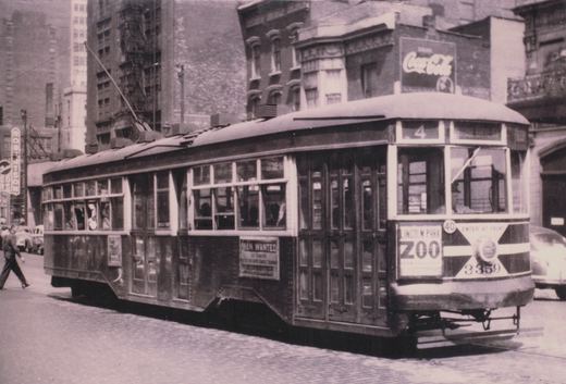 A vintage black-and-white photograph of Chicago Surface Lines streetcar 3359 on a city street, with its destination sign reading 'Cottage Grove Ave' and an ad for Lincoln Park Zoo on the front. The car is on a street lined with buildings and has a Coca-Cola sign on a building above it.
