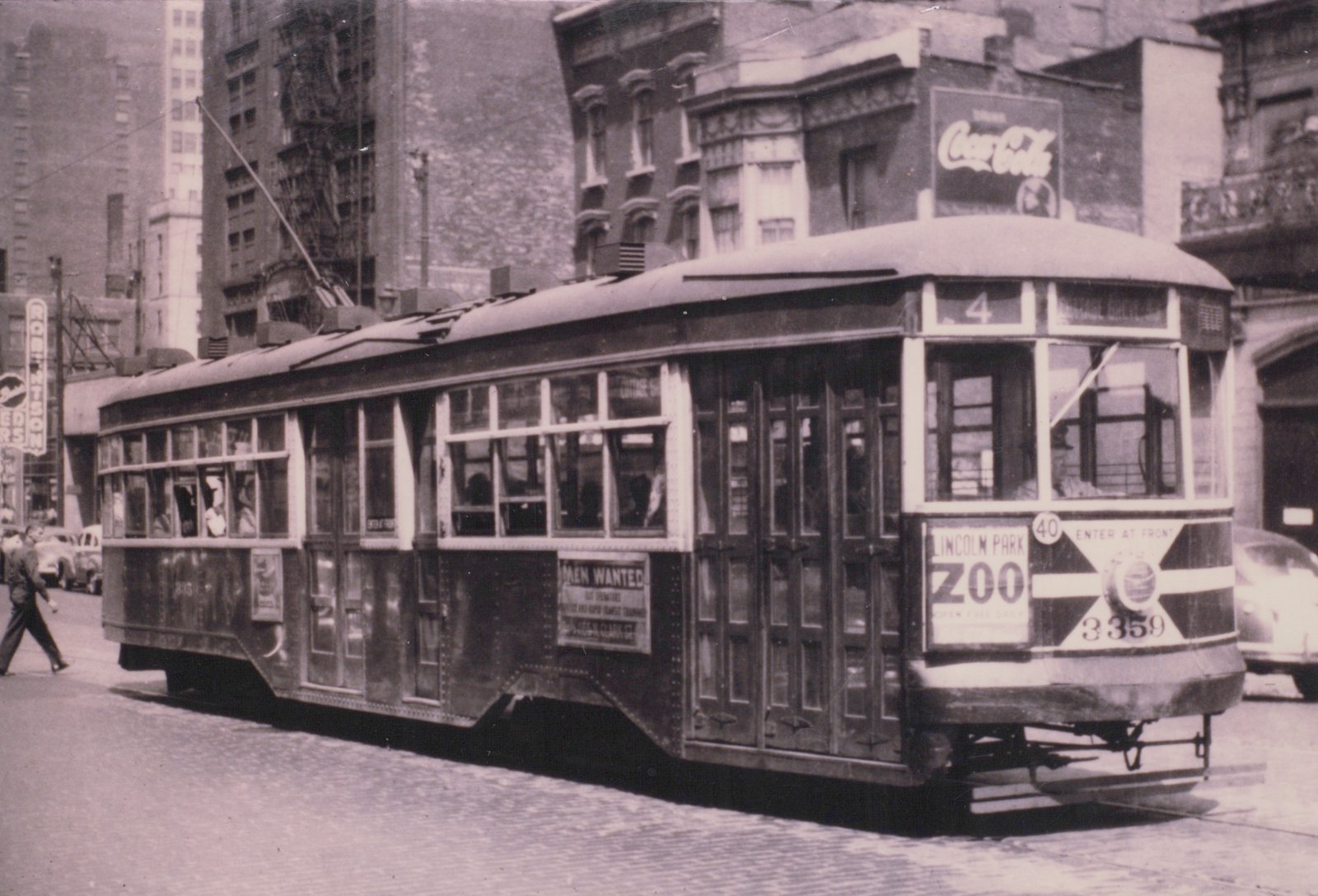 A vintage black-and-white photograph of Chicago Surface Lines streetcar 3359 on a city street, with its destination sign reading 'Cottage Grove Ave' and an ad for Lincoln Park Zoo on the front. The car is on a street lined with buildings and has a Coca-Cola sign on a building above it.