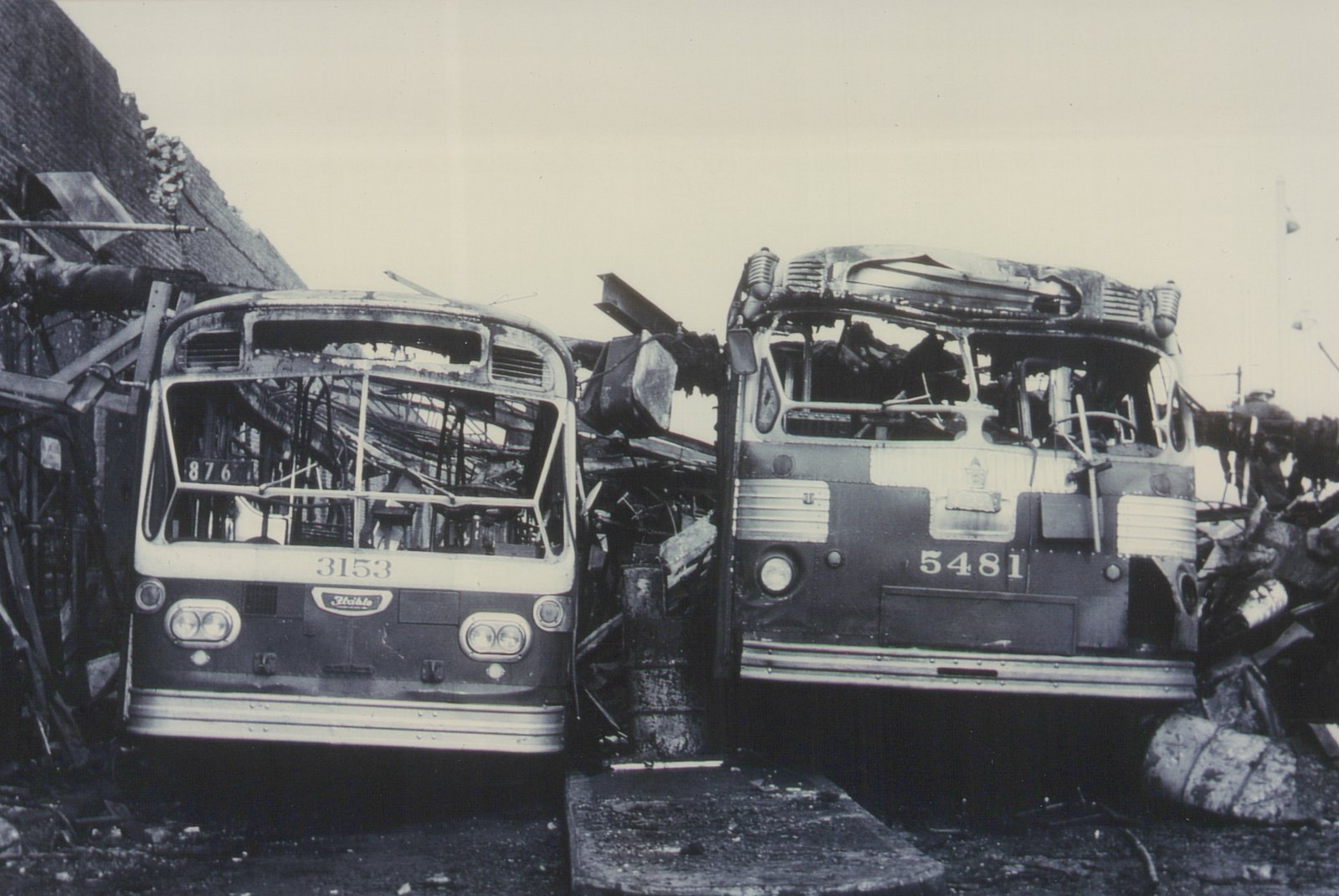 Two burned-out CTA buses, one numbered 3153 and the other 5481, are shown front-on in a wrecked state on a street with debris around them.